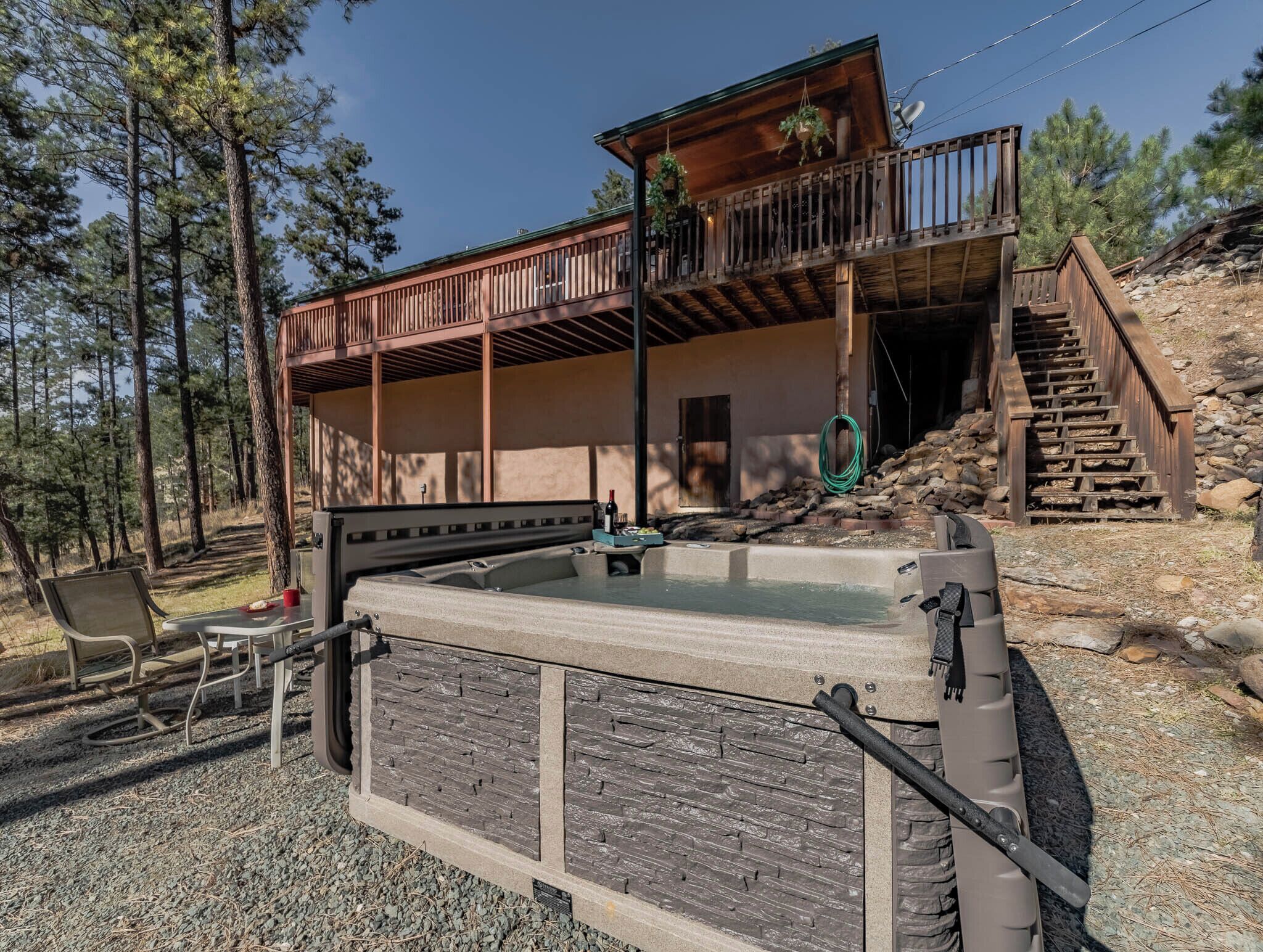 A cabin with a hot tub, outdoor seating, and a wooden deck.