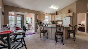 A spacious kitchen with a central island, a dining area with a table and chairs, and a view of the outdoors through a glass door.