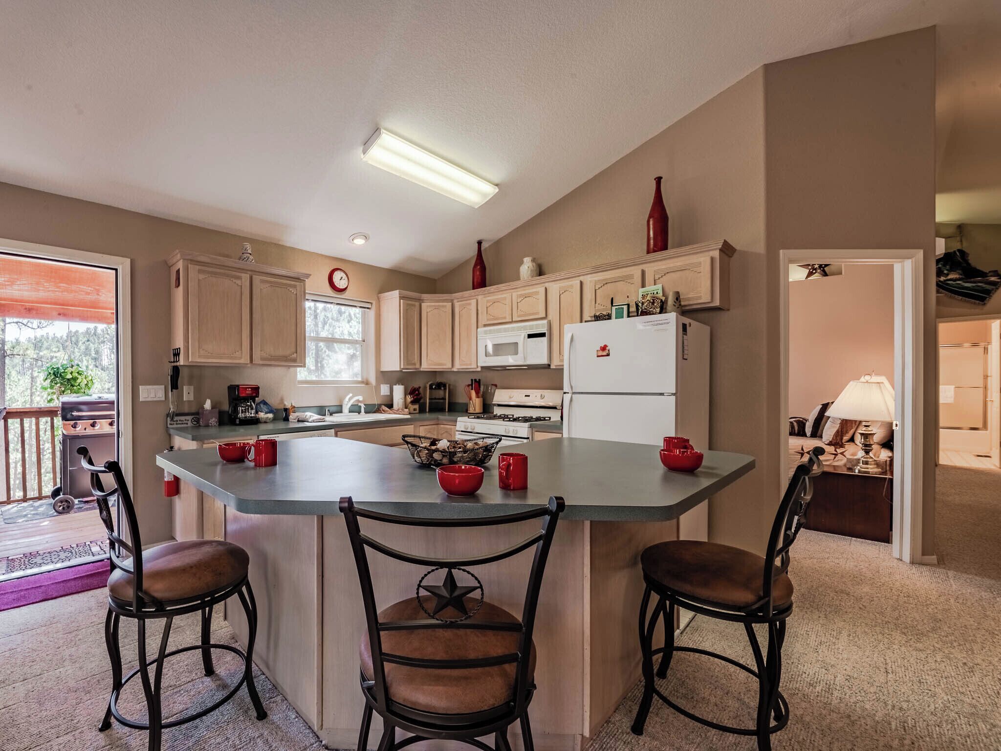 A modern kitchen with a central island, wooden cabinets, and a microwave.