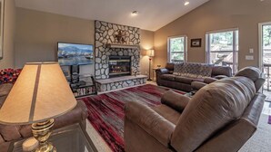 A living room with a stone fireplace, a television, a sofa, and a lamp.