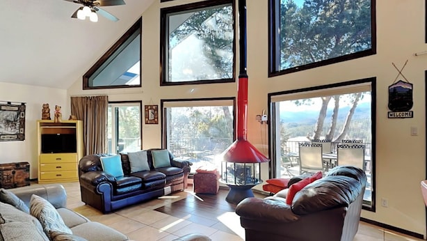 A spacious living room with a large window, a red heater, and a sofa set. - Gray Wolf Lodge by Ruidoso Vacation Rentals (Ruidoso)