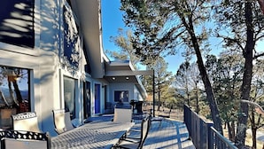 A deck with outdoor furniture and a view of the surrounding landscape. - Gray Wolf Lodge by Ruidoso Vacation Rentals (Ruidoso)