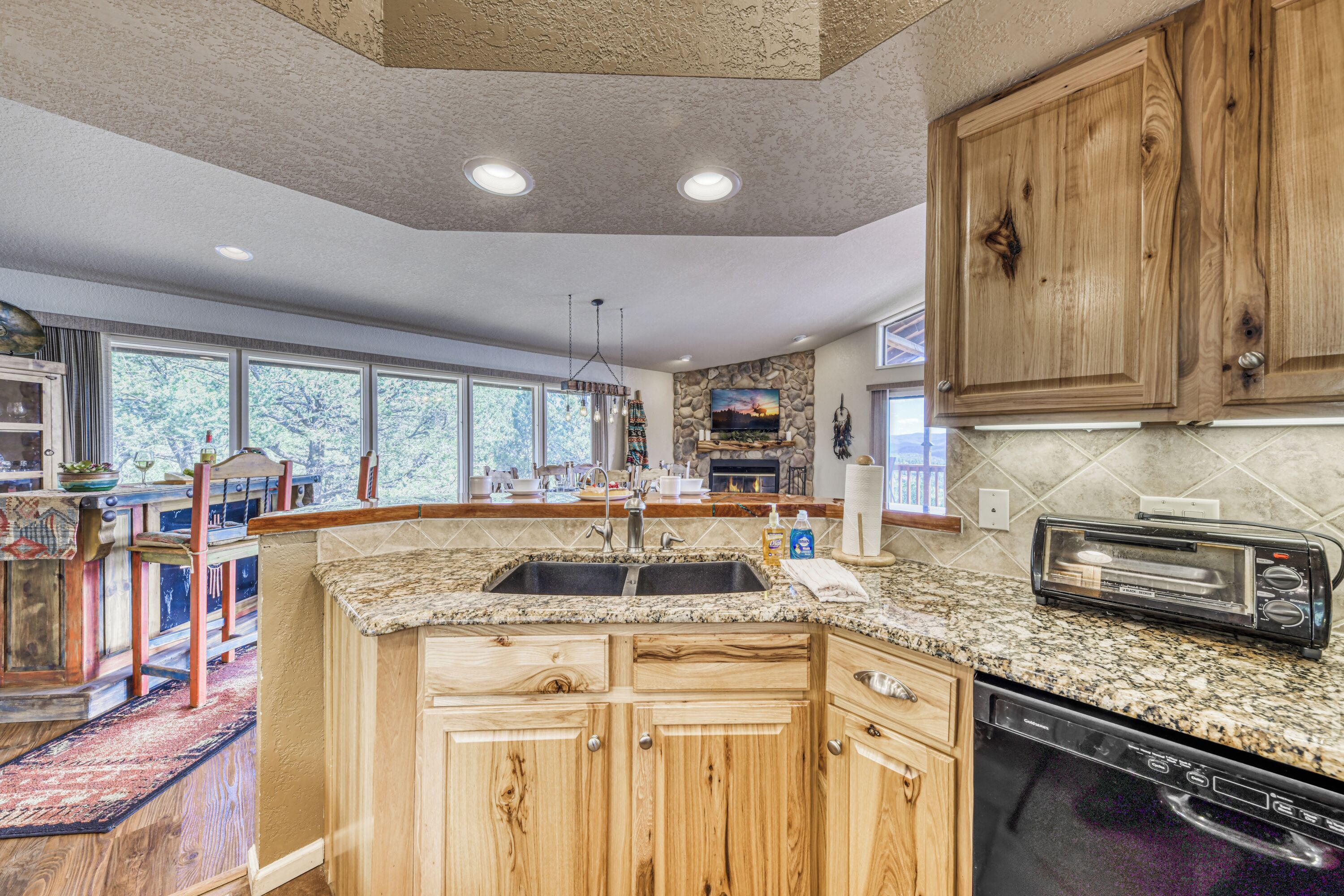A kitchen with wooden cabinets, granite countertops, a dishwasher, and a built-in toaster.