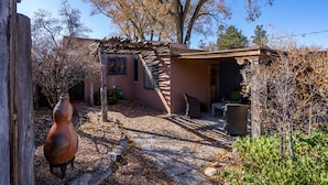 A rustic house with a stone pathway leading to a wooden door. - La Vida Buena by Kokopelli Property Management (Santa Fe)