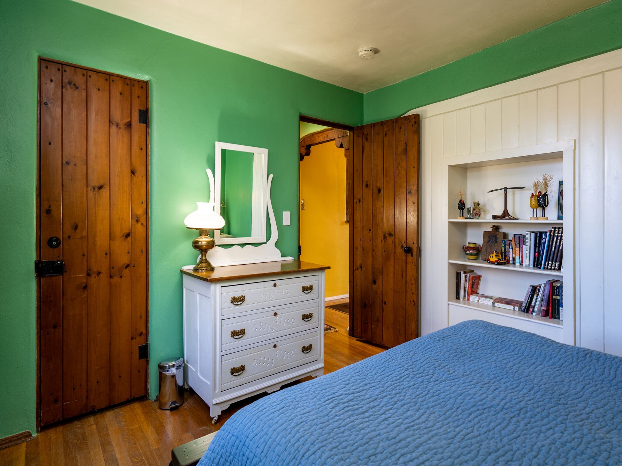 A bedroom with a bed, dresser, and bookshelf.