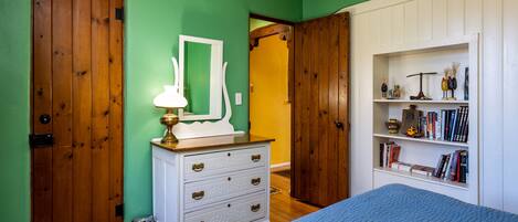 A bedroom with a bed, dresser, and bookshelf.