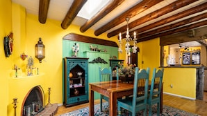 A dining area with a wooden table and chairs, a patterned rug, and a green cabinet with decorative items. - La Vida Buena by Kokopelli Property Management (Santa Fe)