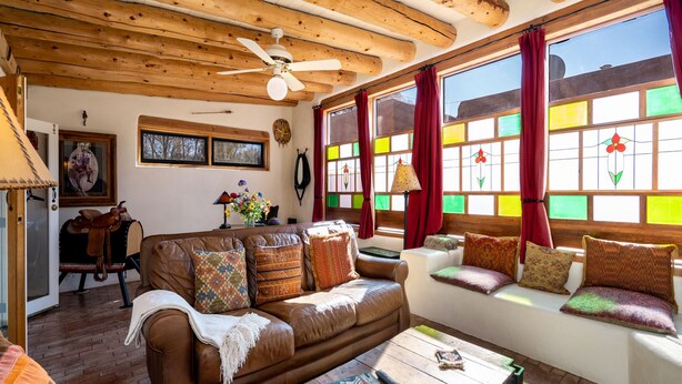 A cozy living room with a brown leather sofa, wooden coffee table, and a ceiling fan. - La Vida Buena by Kokopelli Property Management (Santa Fe)