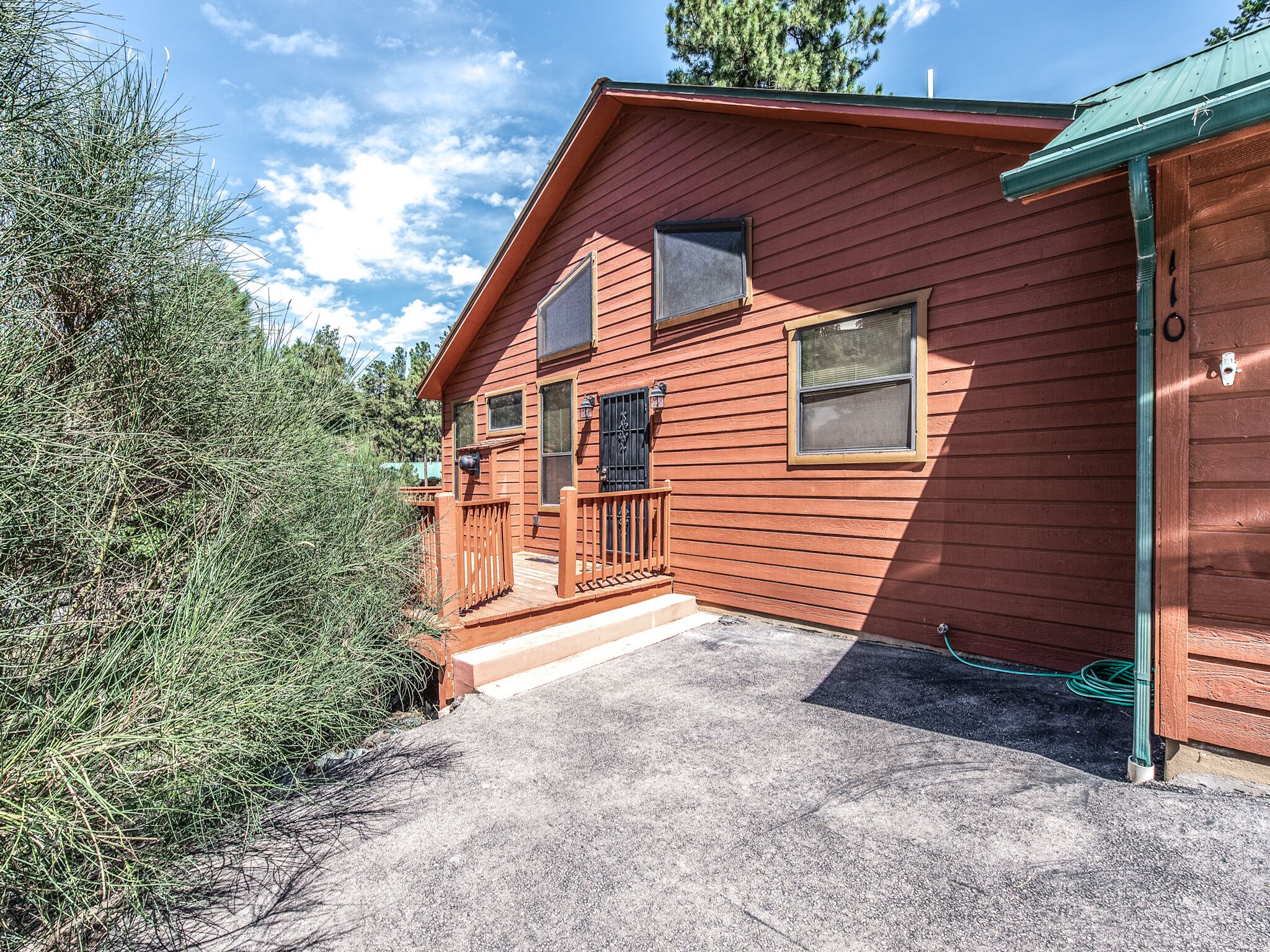 Eine zweistöckige Holzhütte mit Veranda, Garage und kleiner Terrasse.