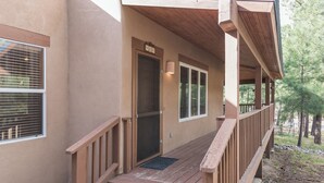 Une terrasse en bois avec une porte portant le numéro « 408 » qui donne sur un porche abrité.
