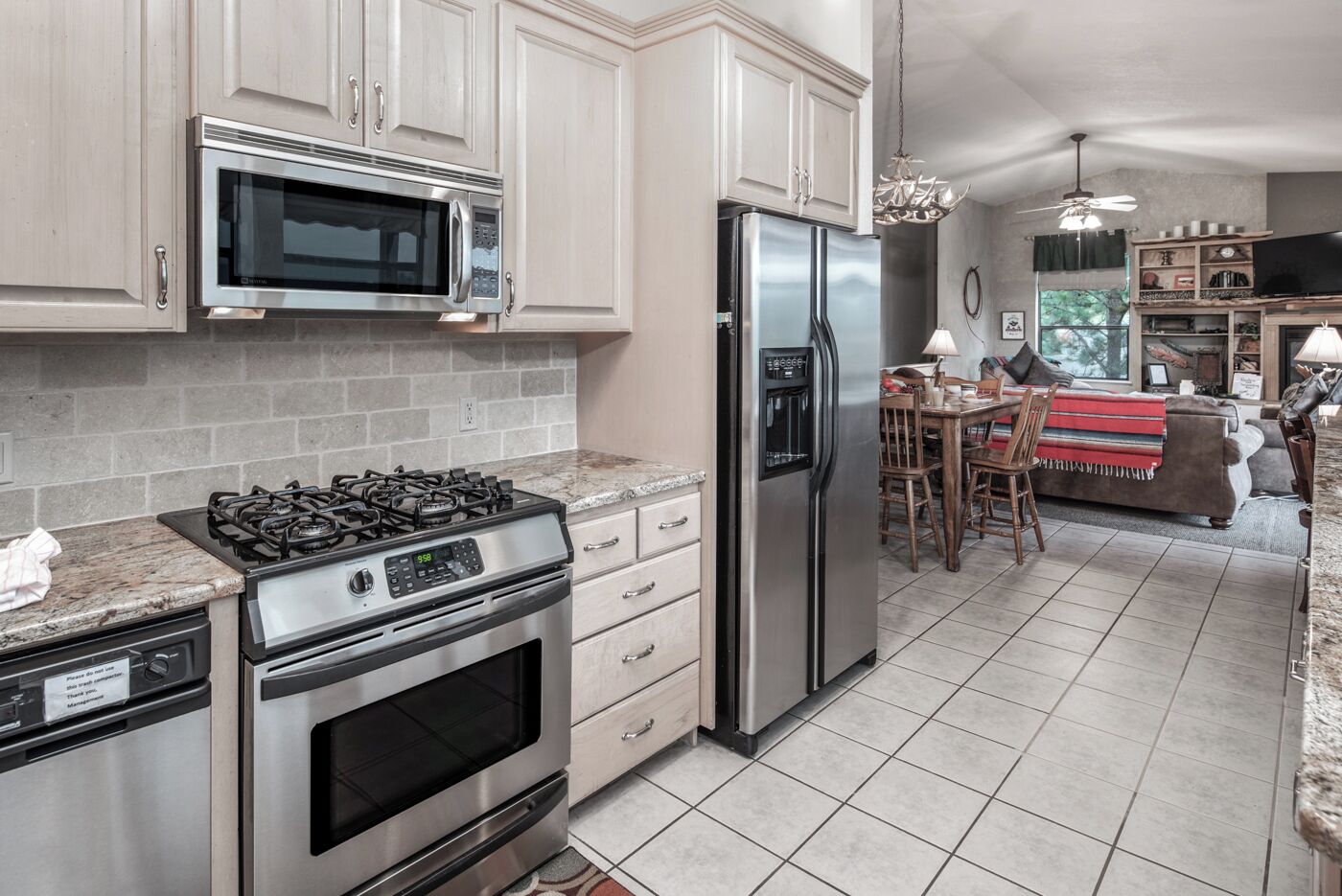 A kitchen with stainless steel appliances, a gas stove, a microwave, and a refrigerator. There is a dining area with a table and chairs.