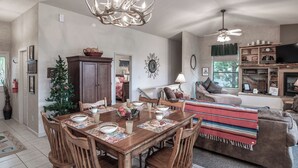 A dining area with a wooden table set for four, surrounded by wooden chairs. There is a Christmas tree and a cabinet in the background. - Robins Nest by Ruidoso Vacation Rentals (Ruidoso)