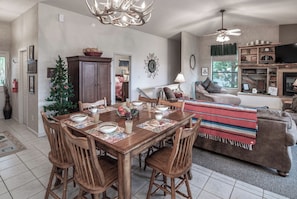 A dining area with a wooden table set for four, surrounded by wooden chairs. There is a Christmas tree and a cabinet in the background. - Robins Nest by Ruidoso Vacation Rentals (Ruidoso)