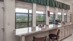 A kitchen with a large island, two bar stools, and a view of the outdoors. - Robins Nest by Ruidoso Vacation Rentals (Ruidoso)