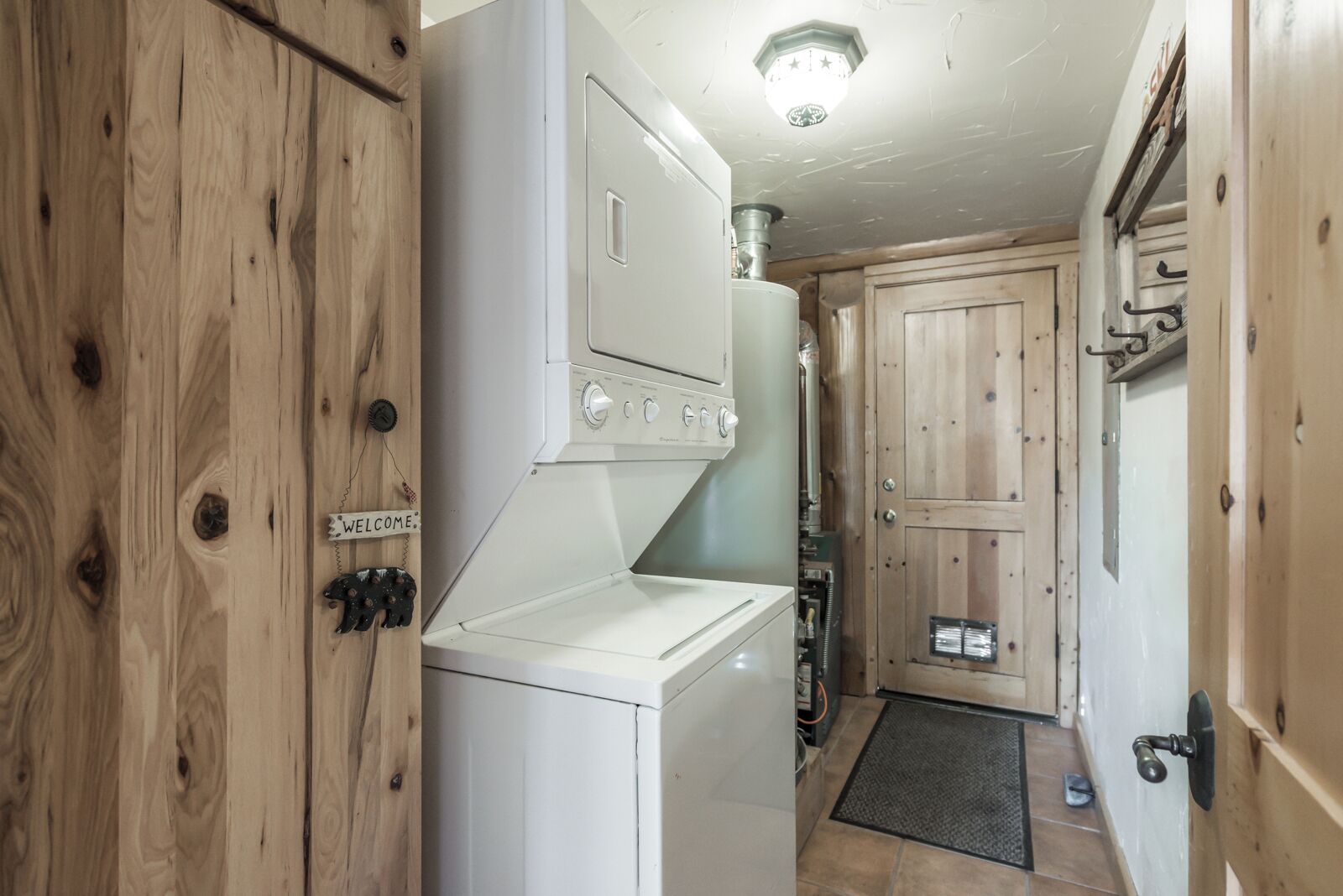 A compact kitchen with a built-in washer and dryer, wooden cabinets, and a small entrance with a door.
