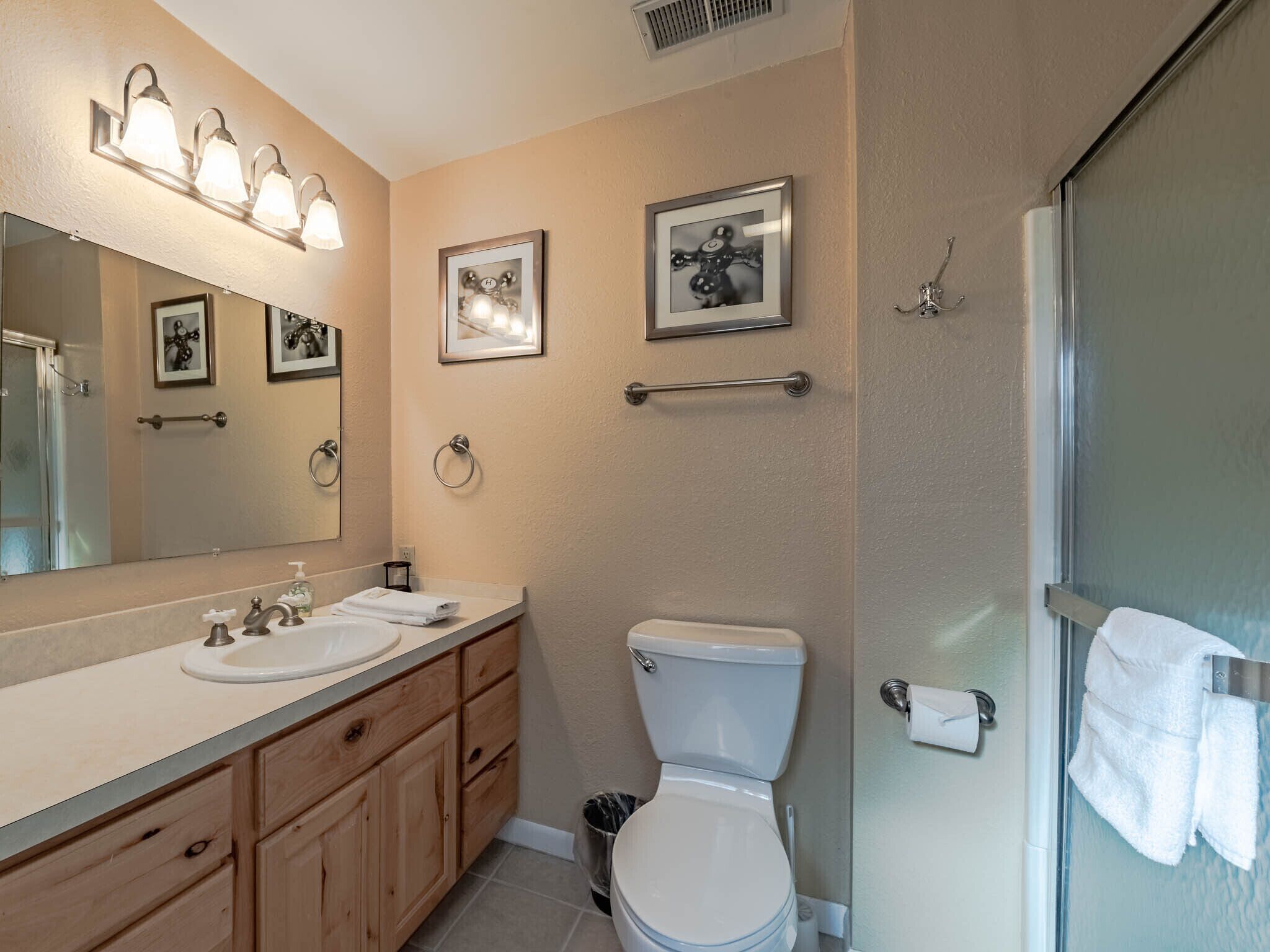 Une salle de bain équipée d’un lavabo, d’un miroir, de toilettes et d’un porte-serviettes.