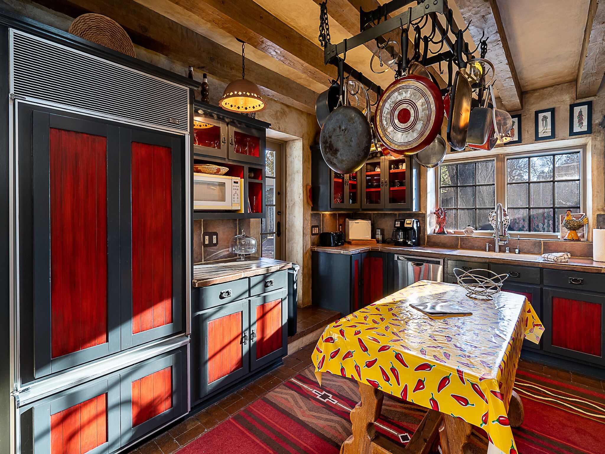 A kitchen with red cabinets, a microwave, and hanging pots.