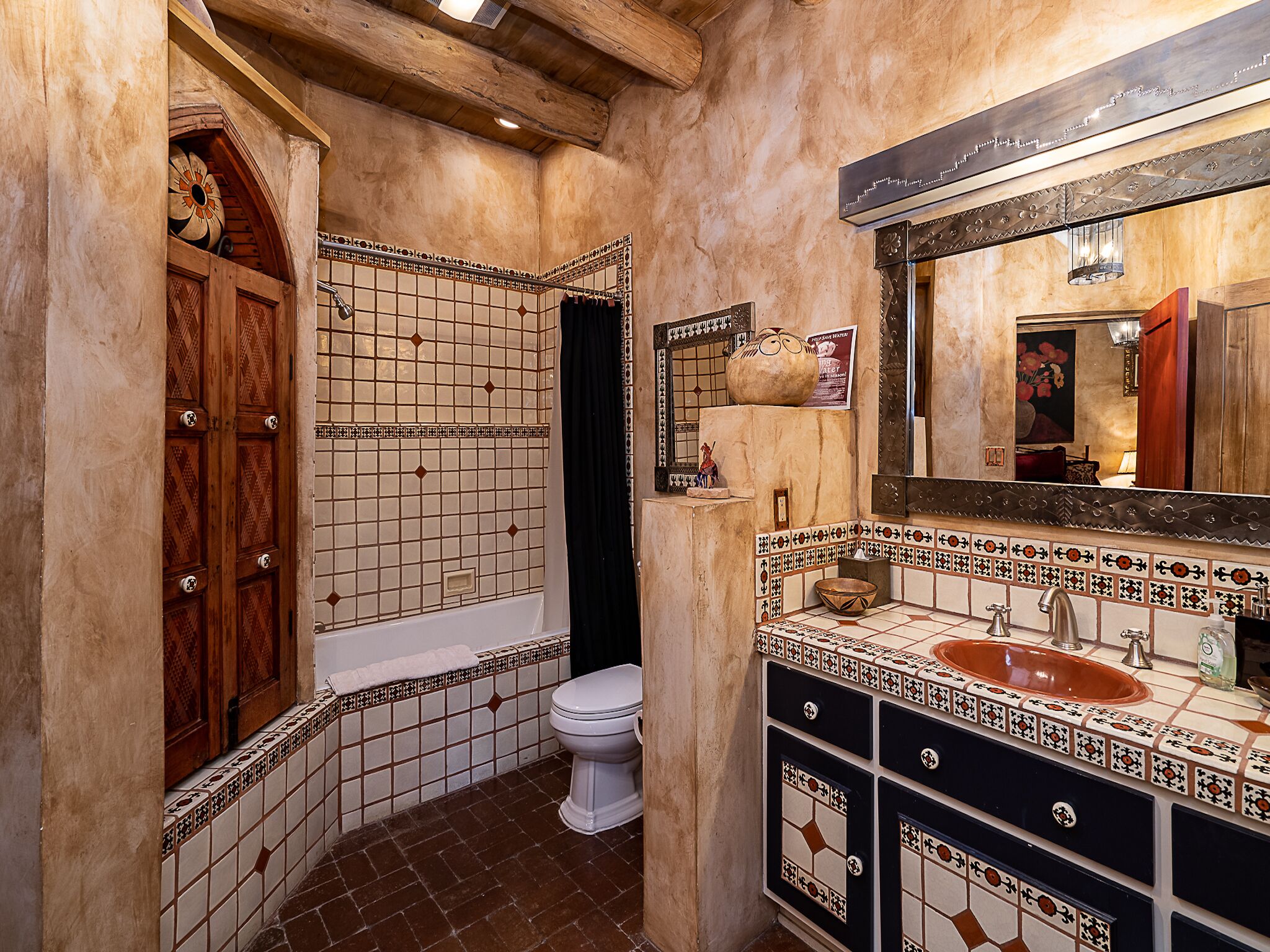 A bathroom with a tiled floor, a white toilet, a bathtub, and a sink with a mirror above it.
