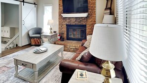 A living room with a fireplace, a sofa, a coffee table, and a lamp. - Ruidoso Rabb by Ruidoso Vacation Rentals (Ruidoso)