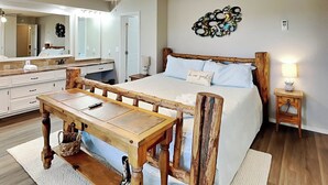 A bedroom with a wooden bed, a wooden nightstand, a bedside table, a ceiling fan, a large mirror, and a wall decoration. - Ruidoso Rabb by Ruidoso Vacation Rentals (Ruidoso)