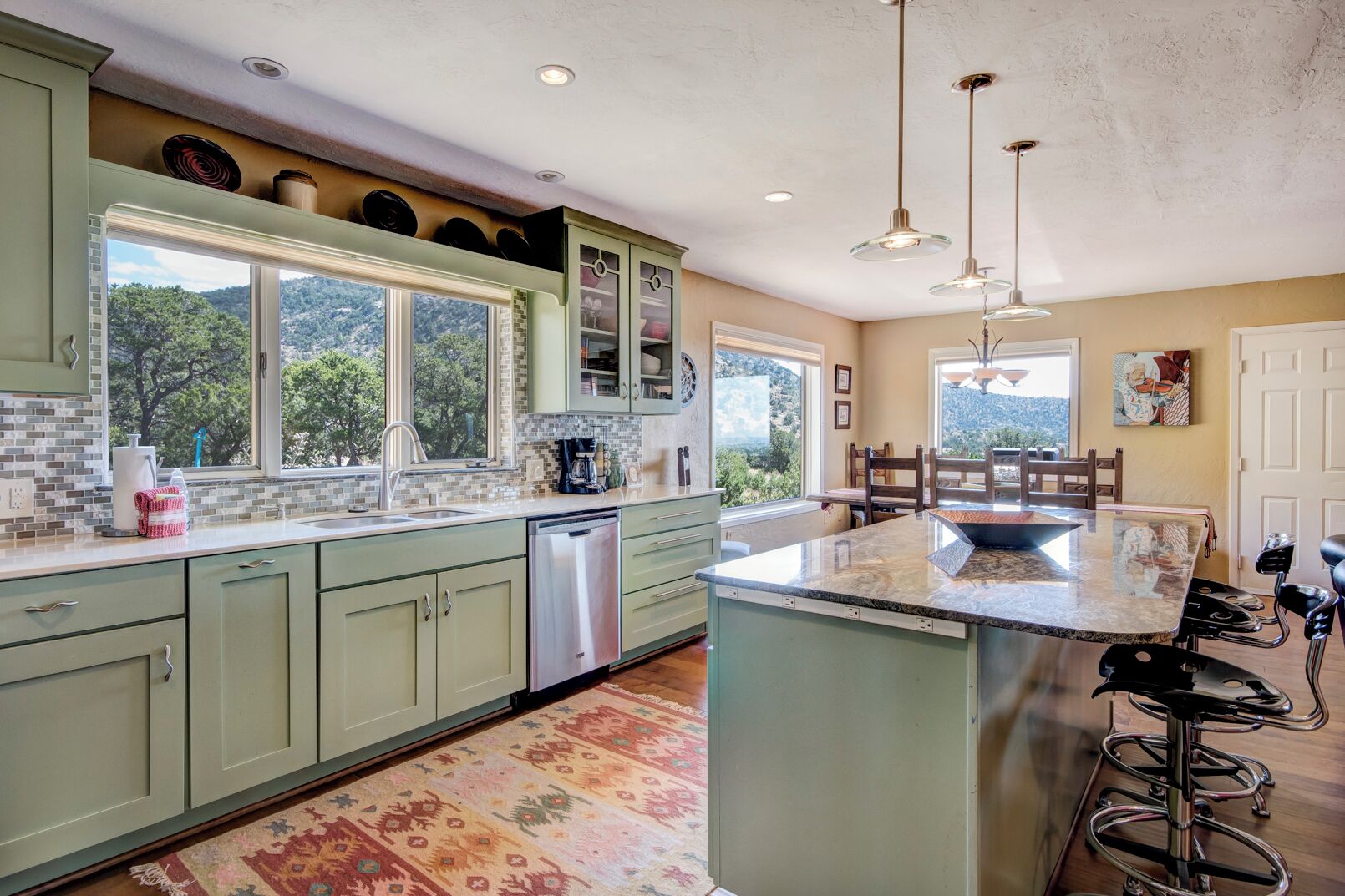 A kitchen with green cabinets, a large island, and a view of the outdoors.