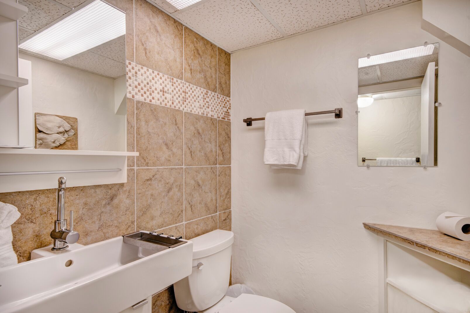 A bathroom with a white sink, a toilet, and a mirror.