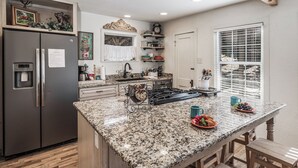 A kitchen with granite countertops, stainless steel appliances, and a window with blinds. - Sugar Butter Chalet by Ruidoso Vacation Rentals (Ruidoso)