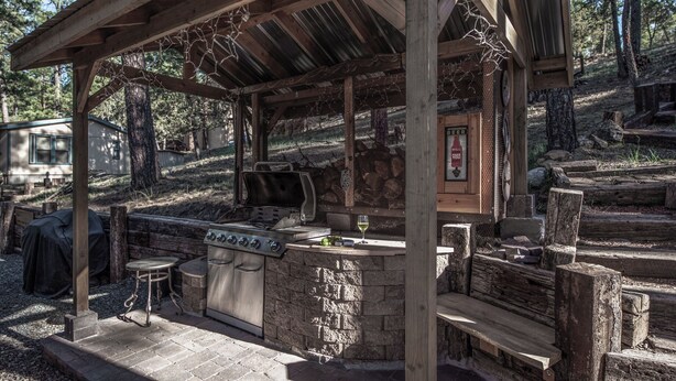 An outdoor barbecue area with a grill, a stone countertop, and a wooden pergola. - Sugar Butter Chalet by Ruidoso Vacation Rentals (Ruidoso)