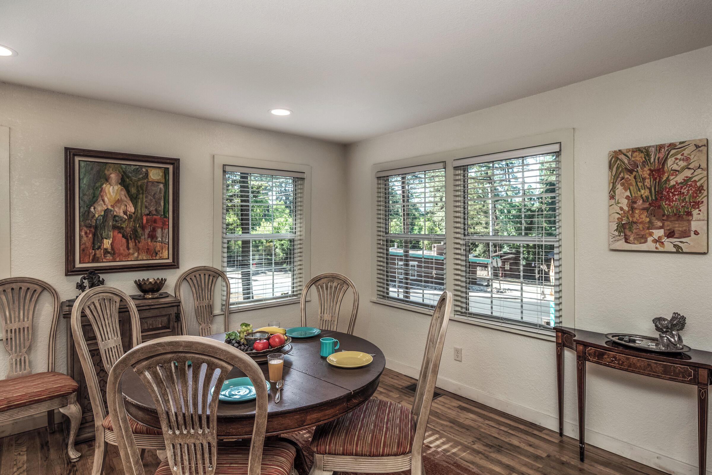 A dining area with a round table, chairs, and artwork on the walls.