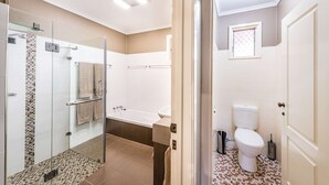 Un baño moderno con ducha envuelta en vidrio, una bañera y un inodoro.