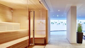 Een modern interieur met houten banken en een glazen scheiding, een betegelde vloer en een plafond met een geometrisch patroon.