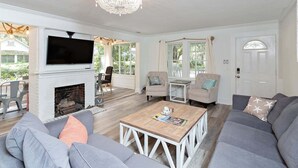 Un salon avec une cheminée, un téléviseur et un lustre.