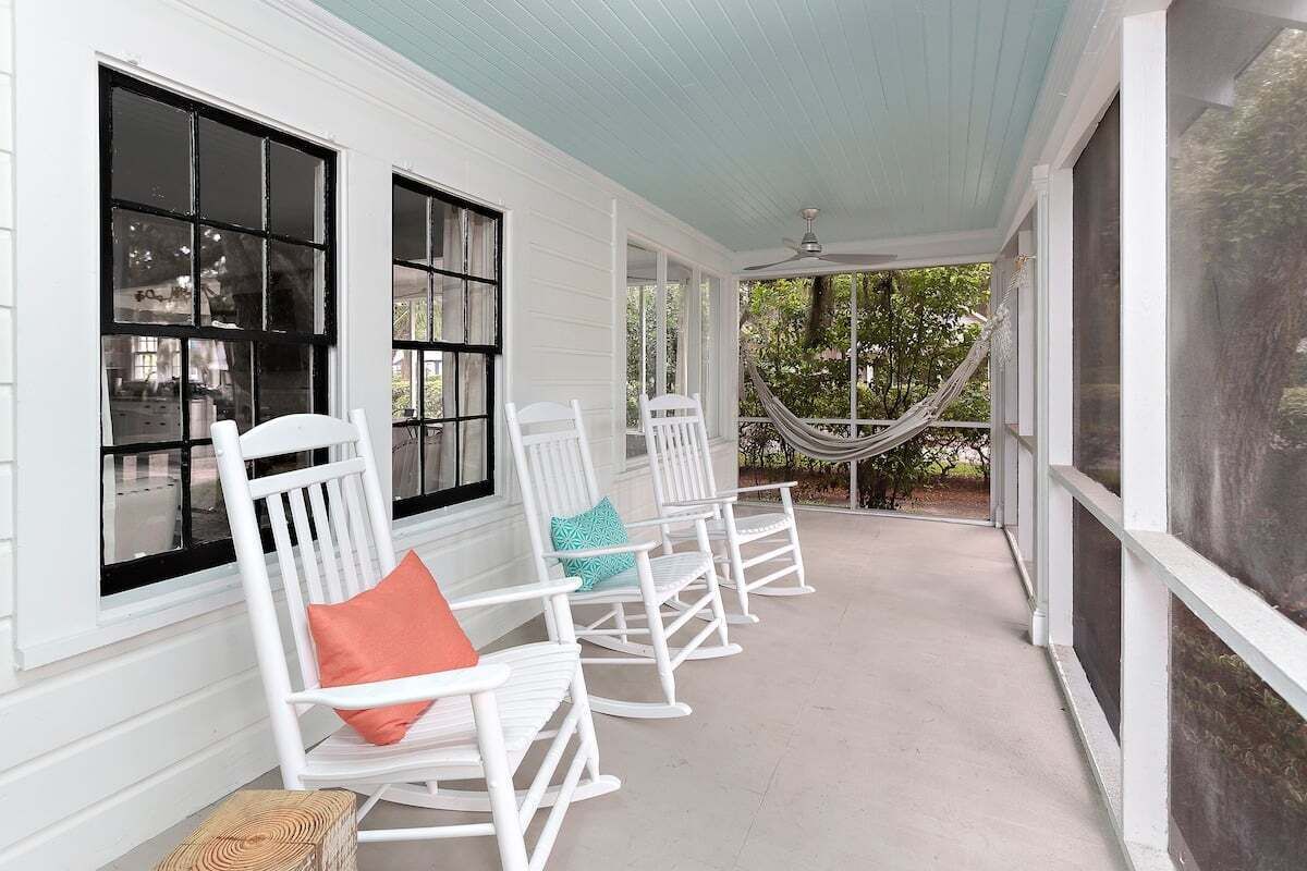 A porch with white rocking chairs and a hammock.
