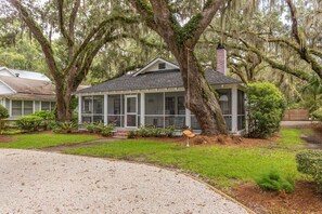 A house with a porch, surrounded by trees and a lawn.