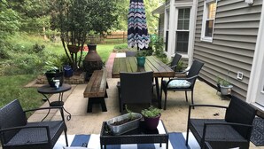 Un espacio al aire libre con patio, una mesa de madera, sillas y un banco.