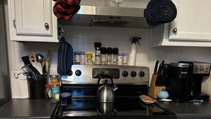 Una cocina con armarios blancos, electrodomésticos de acero inoxidable y una tetera sobre la hornilla.