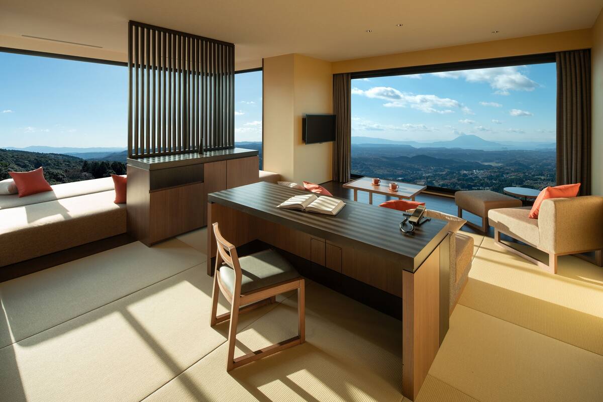 A modern hotel room with a large window offering a panoramic view of the landscape.