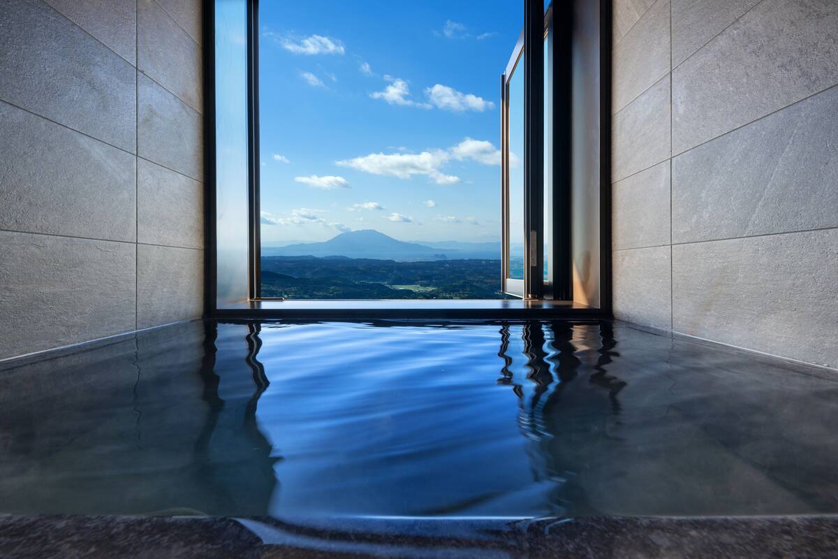 A modern indoor pool with a clear view of a mountain range through large windows.