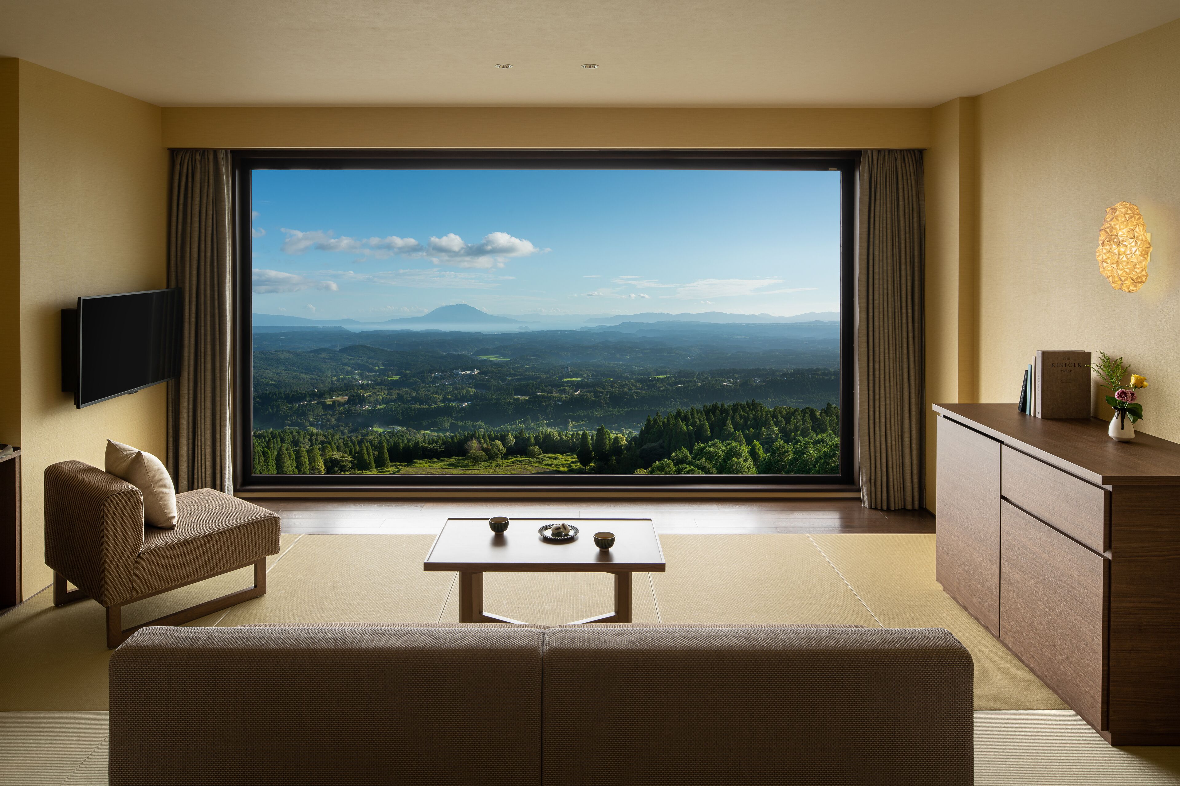 Habitación de hotel moderna con un amplio ventanal que ofrece una vista panorámica de un paisaje montañoso.