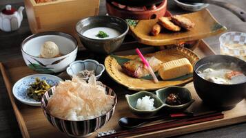 A wooden tray with various Japanese dishes including a bowl of rice, a bowl of soup, and a plate with grilled fish.