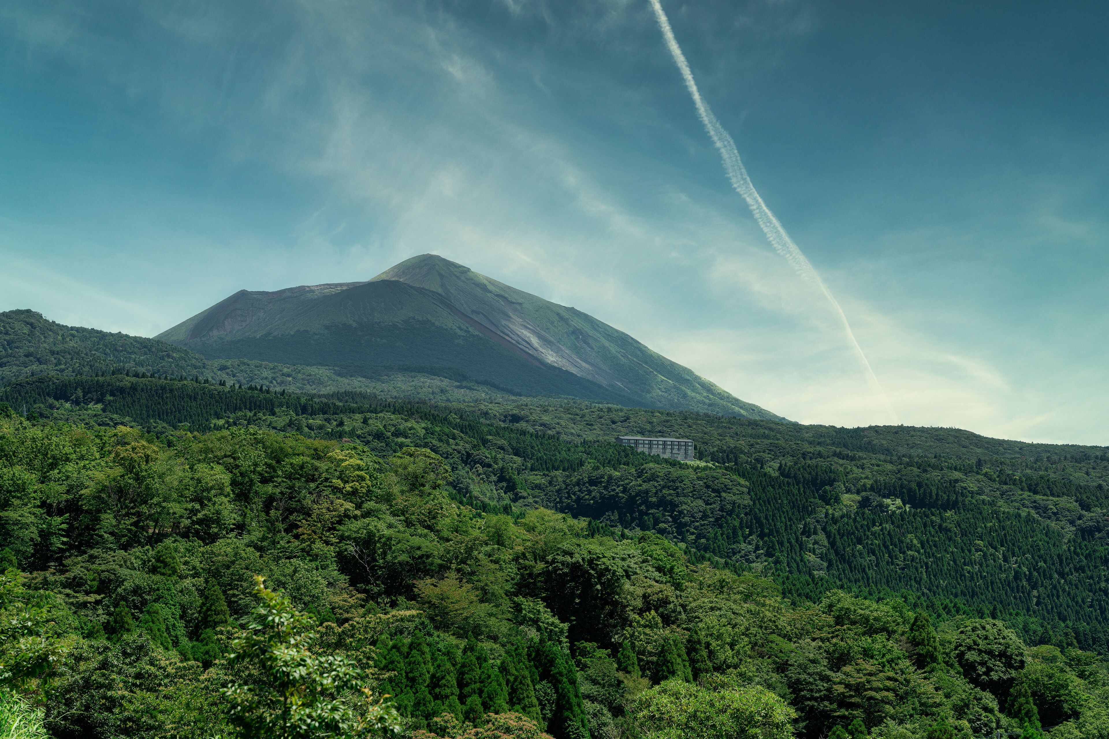 A mountain with a forested slope and a building on the side.