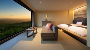 A modern bedroom with a large window, a sofa, a bed, and a small table.