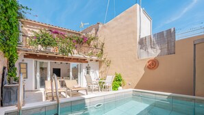 A swimming pool with a glass barrier, outdoor seating, and a building with a balcony. - Holiday Home "Can Raixa" with Private Pool, Private Terrace and Wi-Fi (LLOSETA)