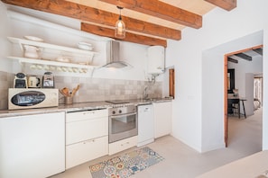Une cuisine moderne avec des meubles blancs, un four encastré, un lave-vaisselle et une hotte de cuisinière en acier inoxydable.