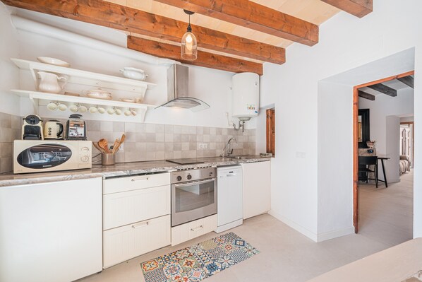 A modern kitchen with white cabinetry, a built-in oven, a dishwasher, and a stainless steel range hood.