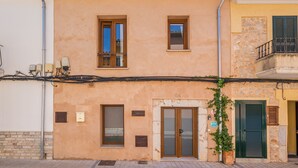 A building with a tiled roof, a balcony with a metal railing, and a door with a glass panel. - Holiday Home "Can Raixa" with Private Pool, Private Terrace and Wi-Fi (LLOSETA)