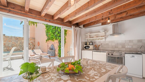 A modern kitchen with a dining area, wooden ceiling beams, and a view of the outdoors. - Holiday Home "Can Raixa" with Private Pool, Private Terrace and Wi-Fi (LLOSETA)