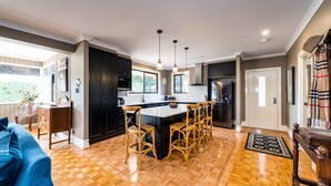 Une cuisine spacieuse avec un îlot central, des meubles de couleur noire et un plancher en bois.