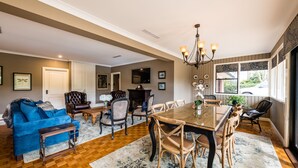 Un salon spacieux avec une grande table à manger en bois, des sièges confortables et un lustre.