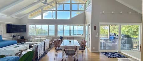 A spacious living area with a high ceiling, a dining table, and a seating arrangement.